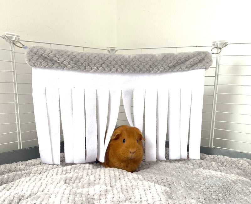 ginger guinea pig hiding in gray kavee fleece corner curtain in c and c cage laying on gray fleece liner