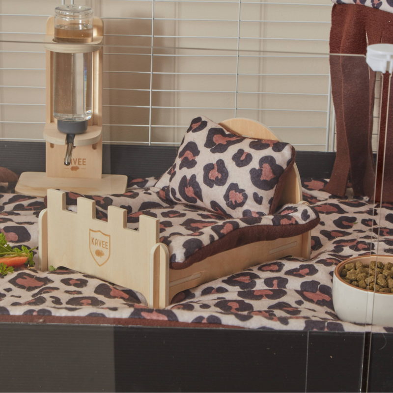 a kavee wooden bed with leopard print pillow and pee pad on top