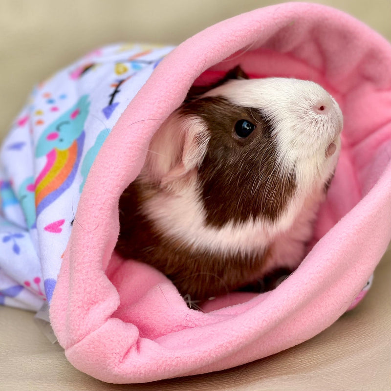 brown and white guinea pig in a pink fleece sleepbag with unicorn from kavee
