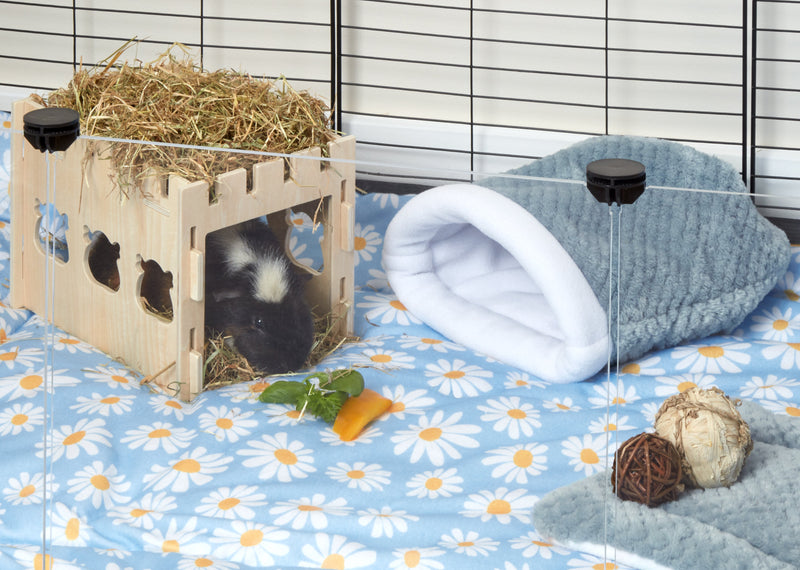 blue fleece sleep sack next to guinea pig hiding in wooden castle tunnel sitting on daisy print fleece liner in c and c cage